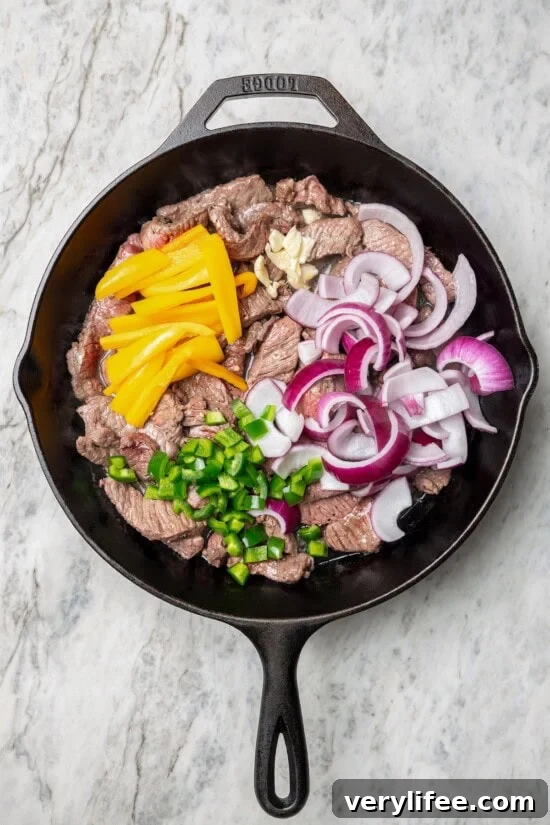 Peruvian Lomo Saltado: Authentic Stir-Fried Beef and Fries 9 Overhead view of vegetables added to beef in skillet