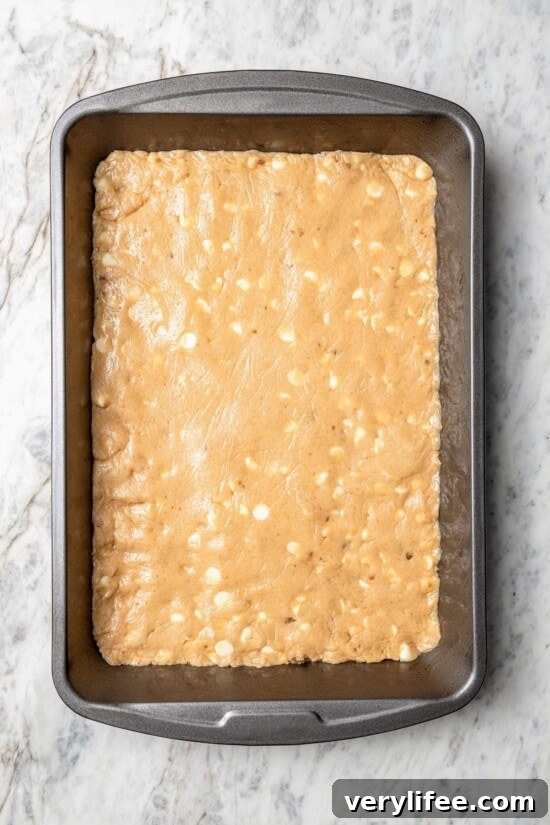 Overhead view of sugar cookie dough with white chocolate chips on sheet pan