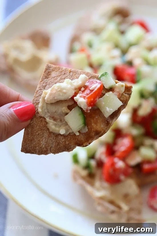 These Greek Nachos are a healthier Greek twist on traditional nachos. They are made with whole wheat pita chips, hummus, cucumbers, tomatoes and feta.