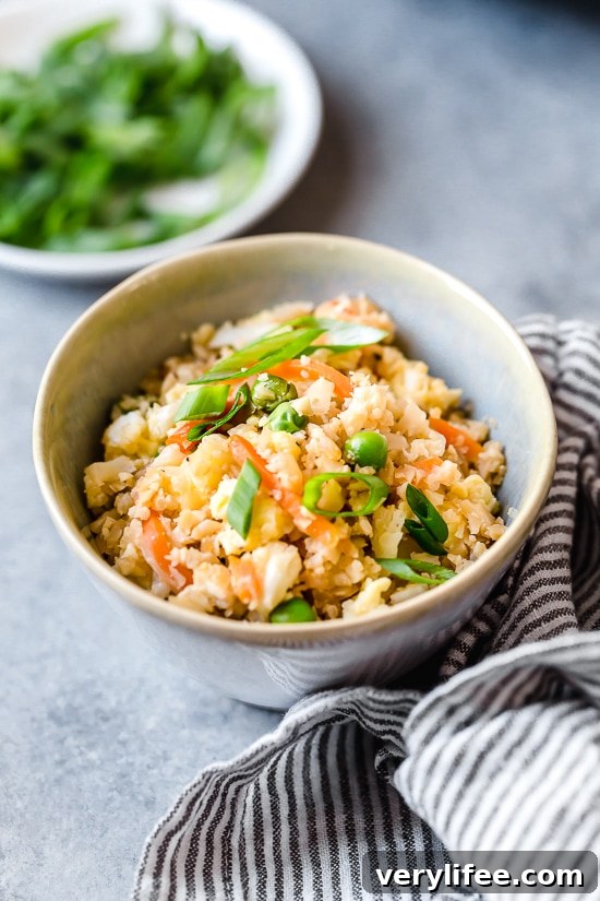 This low-carb cauliflower fried rice recipe is quick, flavorful and a great way to enjoy your favorite takeout-style dish in a lighter way! Bowl of cauliflower fried rice with scallions.