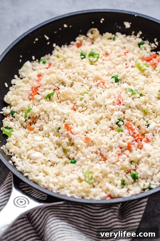 Cauliflower Fried Rice Recipe for Low-Carb Stir-Fry 5 Cauliflower rice added to skillet with vegetables.