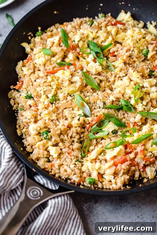 Cauliflower Fried Rice Recipe for Low-Carb Stir-Fry 6 Cauliflower fried rice in skillet with vegetables and eggs.