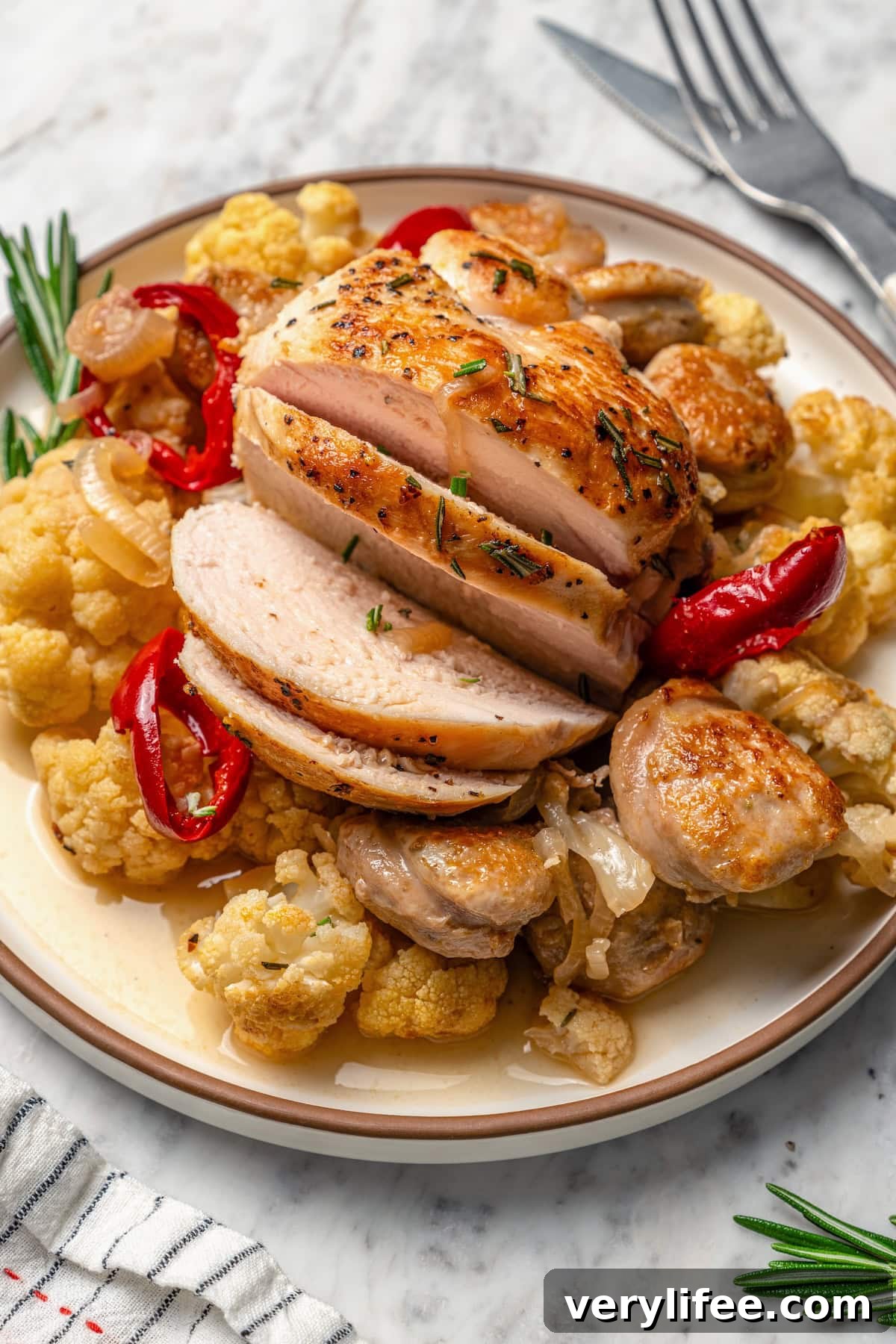 Low-Carb Chicken Scarpariello Recipe 9 Sliced chicken scarpariello on plate with sausage and cauliflower.