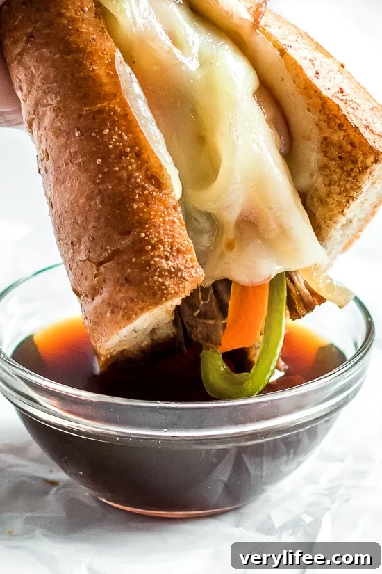 Slow Cooker French Dip Sandwich with Caramelized Onions filled with beef, melted cheese and au jus (beef broth) for dipping.
