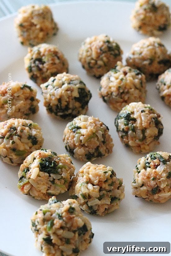 Baked Mini Spinach and Sausage Arancini Bites 2 A plate of brown rice balls with crumbled sausage and pieces of spinach