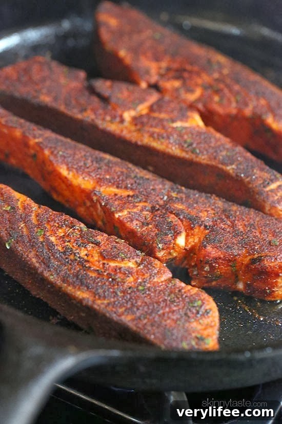 Cajun Blackened Salmon with Mango Salsa 5 Blackened salmon fillets cooking in a cast-iron skillet