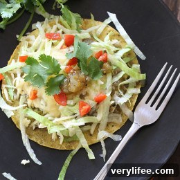 Tomatillo Huevos Rancheros on a tostada with cheese, lettuce, tomato, and cilantro