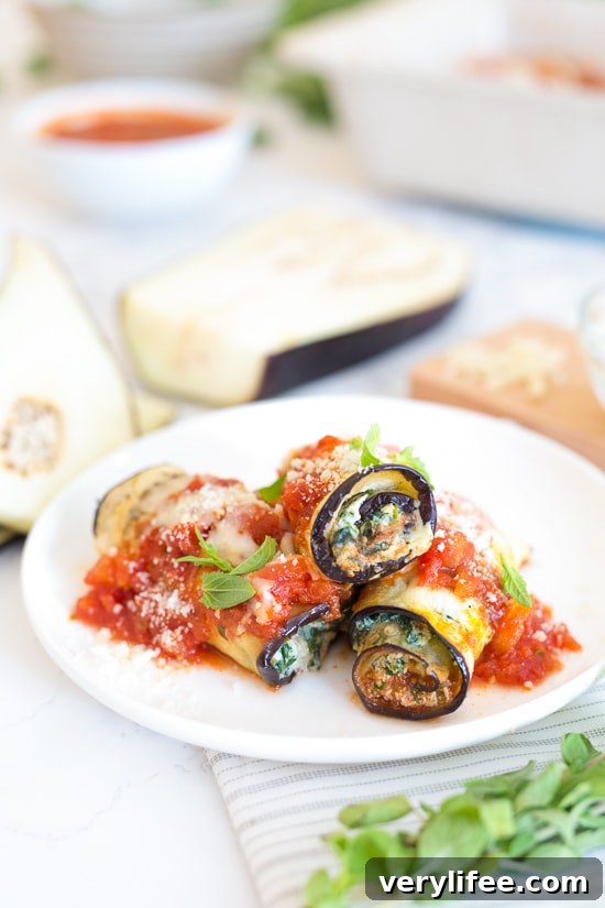 Three eggplant rollatini with sauce on a plate.