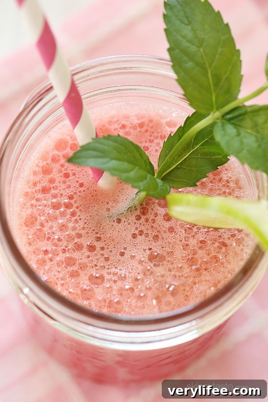 Chilled watermelon agua fresca poured into a glass with ice.