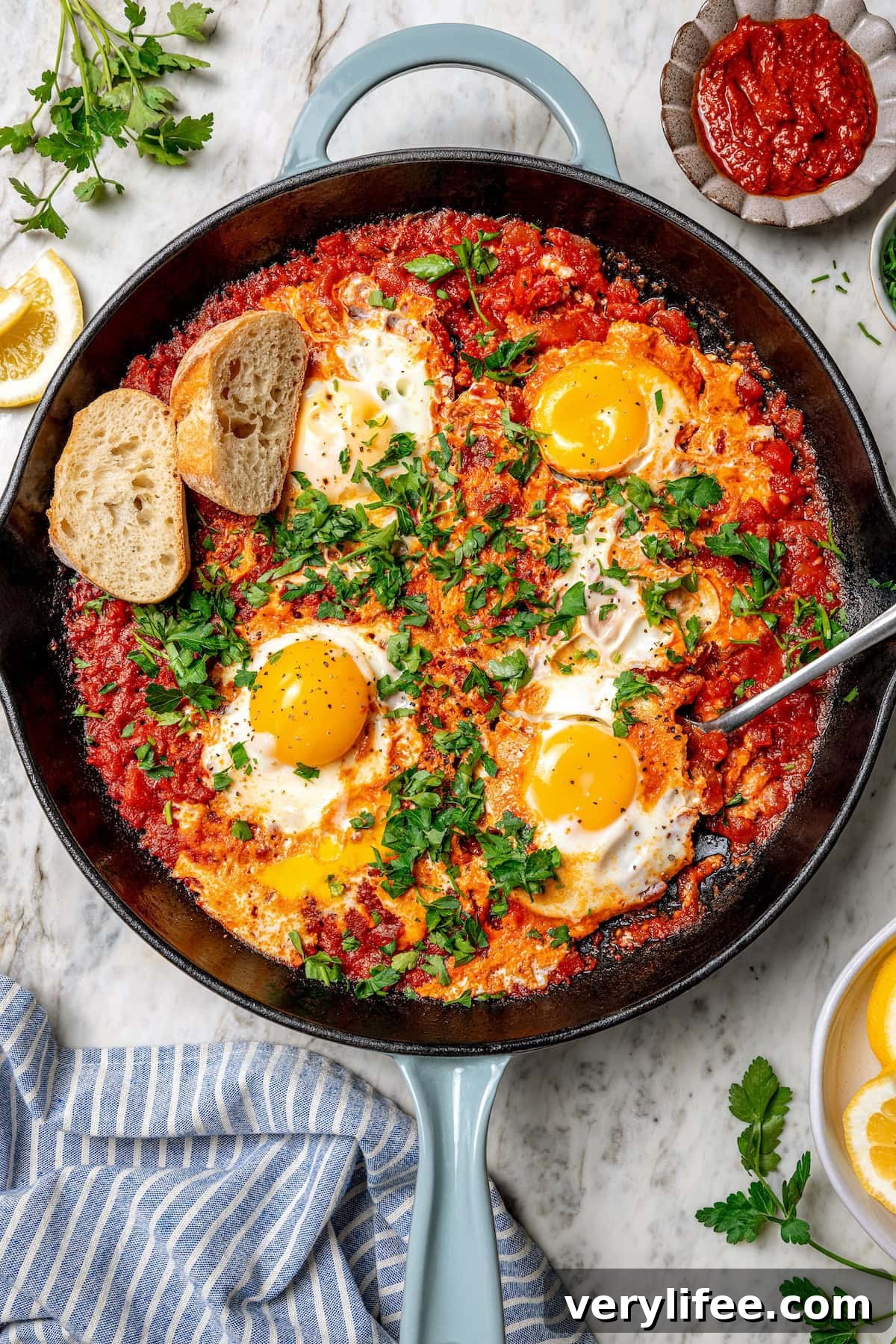 Eggs in purgatory with harissa Overhead view of eggs in purgatory in skillet with spoon and 2 slices of bread