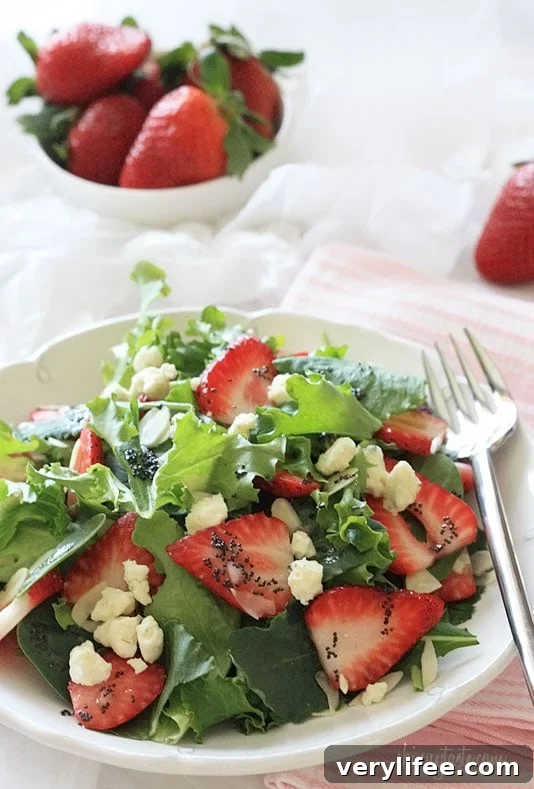 Strawberry salad made with mixed greens, kale and spinach, sliced almonds, crumbled gorgonzola cheese and topped with poppy seed dressing – perfect for summer!