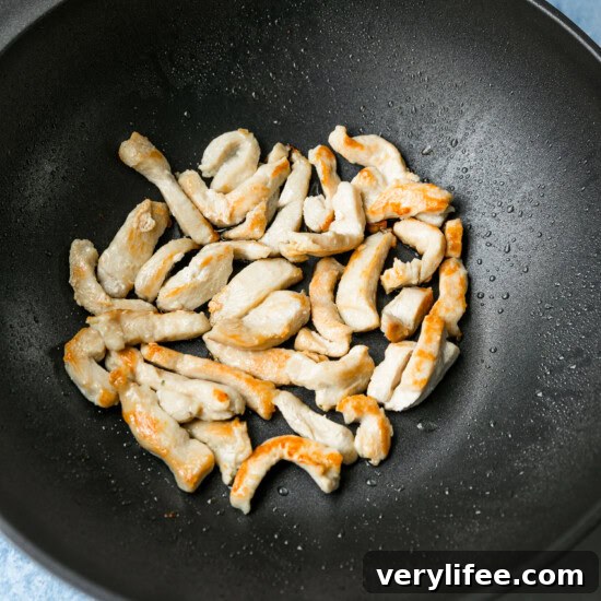 Quick Chicken and Vegetable Stir Fry Recipe 5 Thinly sliced chicken browning in a wok.