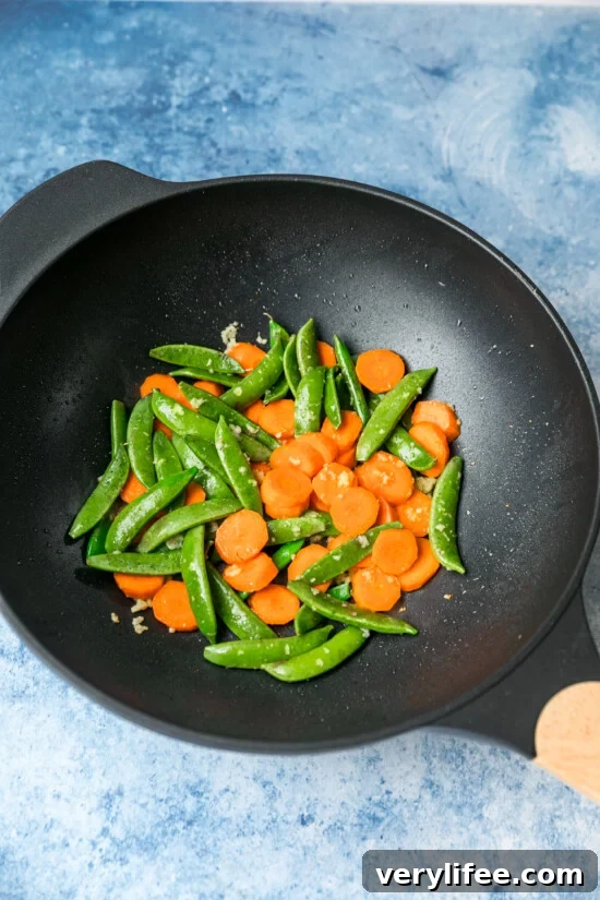 Quick Chicken and Vegetable Stir Fry Recipe 6 Snap peas and carrots sautéed with ginger and garlic in a wok.