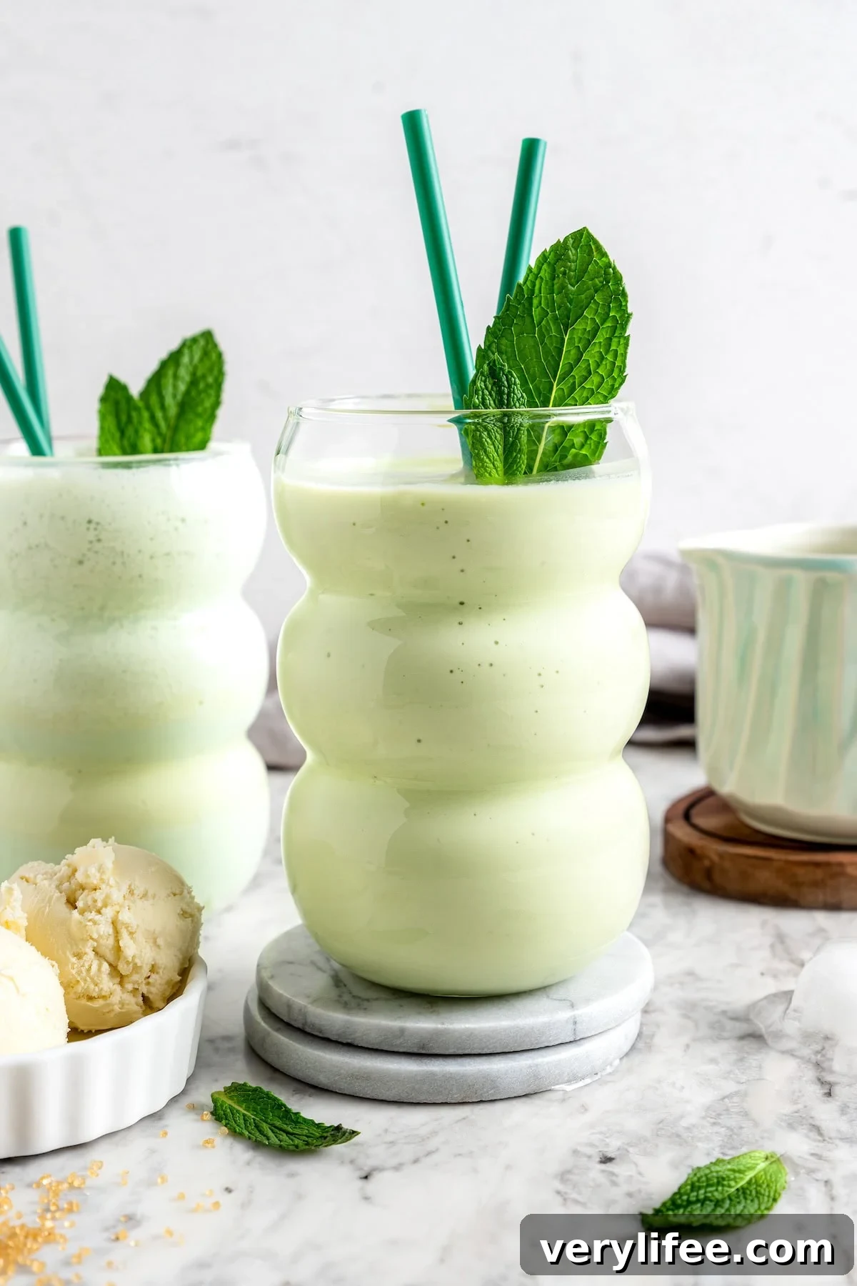 Skinny shamrock shakes in glasses with straws and fresh mint leaves