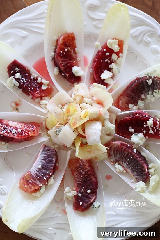 Blood Orange Endive Salad with Citrus Vinaigrette 6 A plate of endive pieces with a blood orange segment in each, topped with crumbled Gorgonzola cheese and blood orange vinaigrette