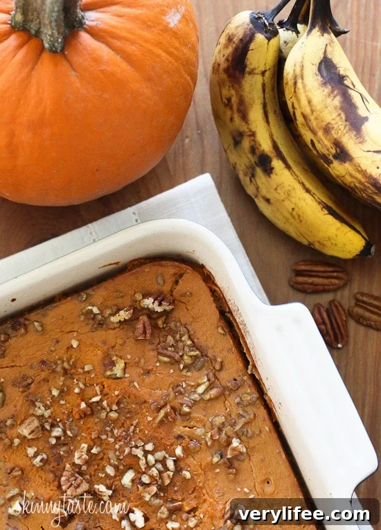 A casserole dish with pumpkin baked oatmeal next to a pie pumpkin and bunch of ripe bananas