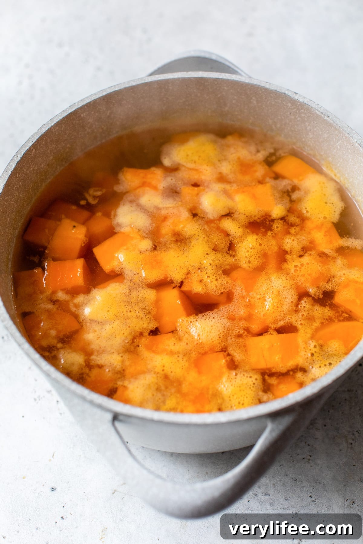 Cubed sweet potatoes boiling in a pot of water.