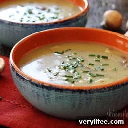 Bowl of creamy mushroom soup with fresh mushrooms nearby