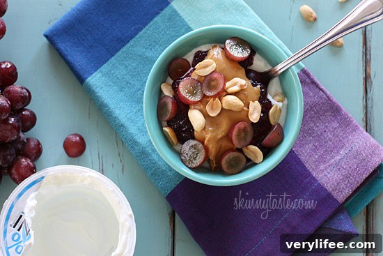 Peanut butter, grape jam, peanuts, and fresh red grapes on top of a bowl of yogurt... who needs the bread!