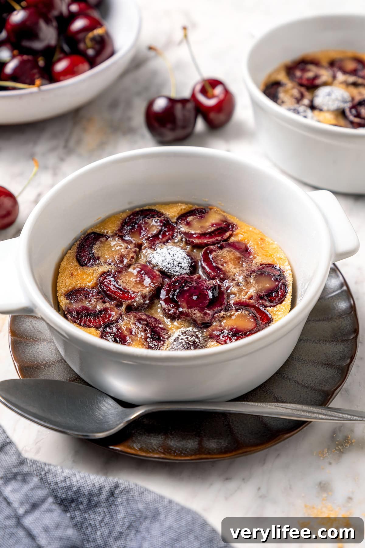 Cherry clafoutis in ramekin with powdered sugar dusted on top.