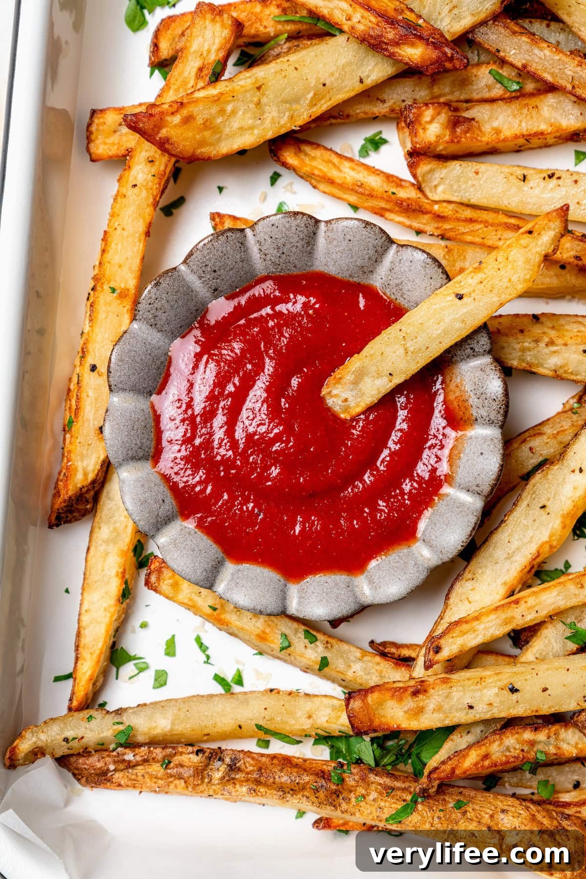 A healthy recipe for homemade ketchup with no high fructose corn syrup. Instead it's sweetened naturally with honey and it tastes amazing! French fry dipping into small bowl of ketchup