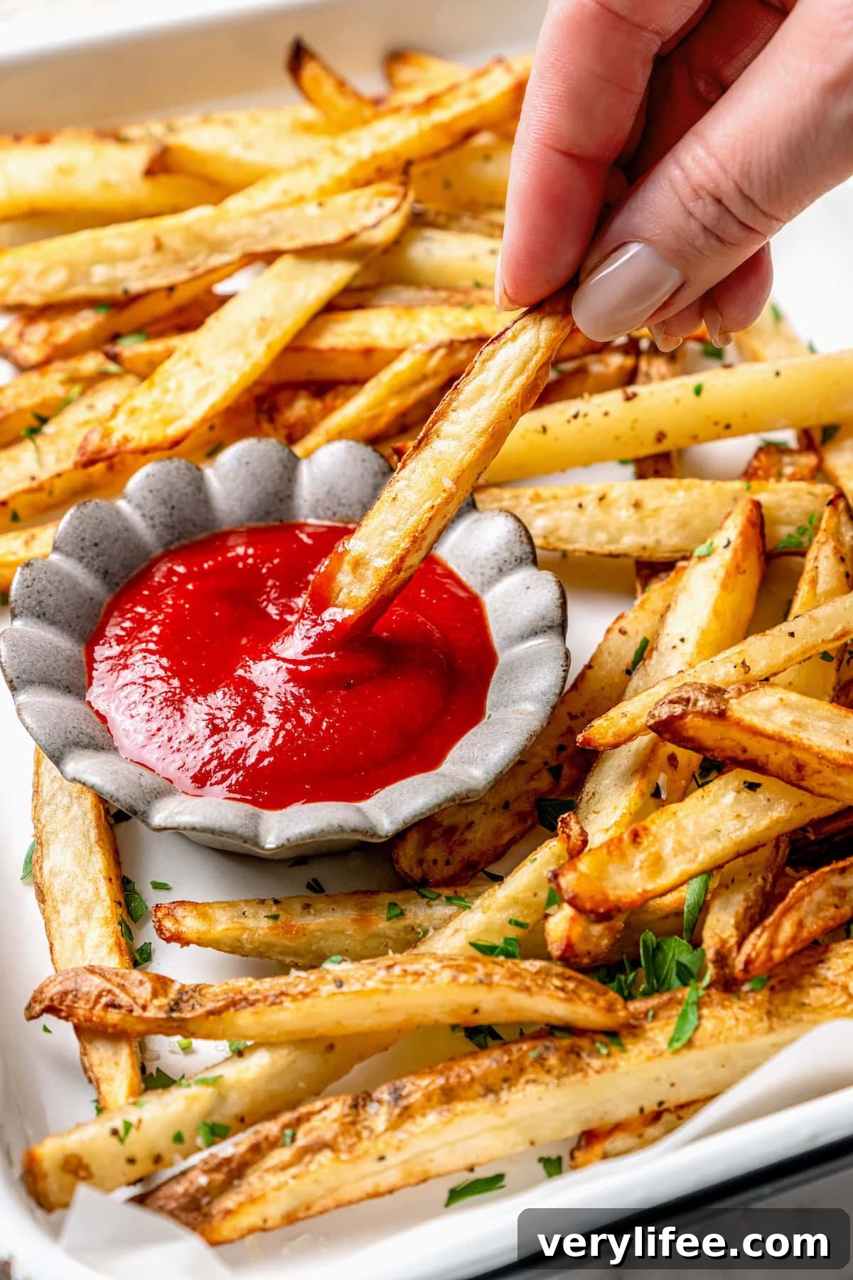 How to Make Homemade Ketchup from Scratch 9 Hand dipping fry into bowl of homemade ketchup