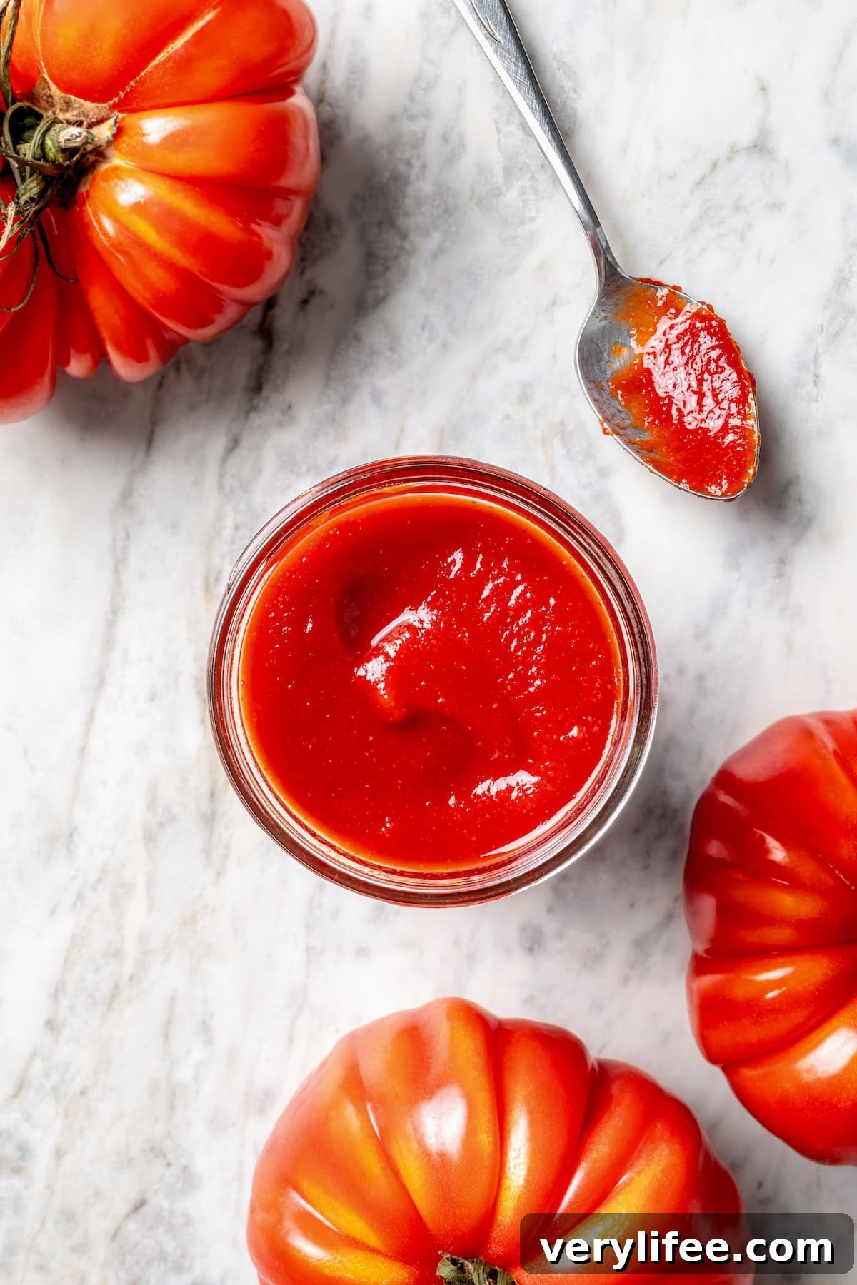 How to Make Homemade Ketchup from Scratch 8 Overhead view of homemade ketchup in jar and spoon, surrounded by fresh heirloom tomatoes