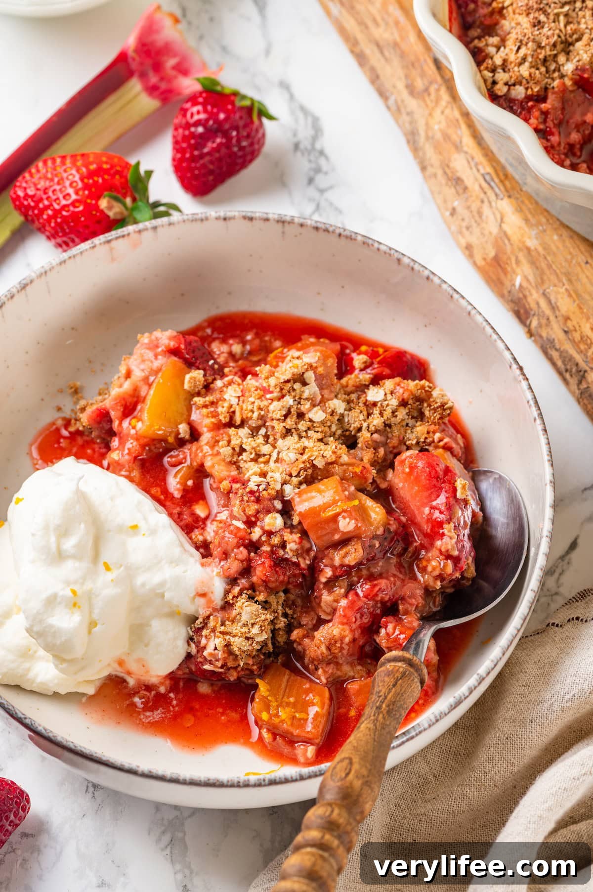Perfect with whipped cream Bowl of strawberry rhubarb crisp with scoop of whipped cream and spoon