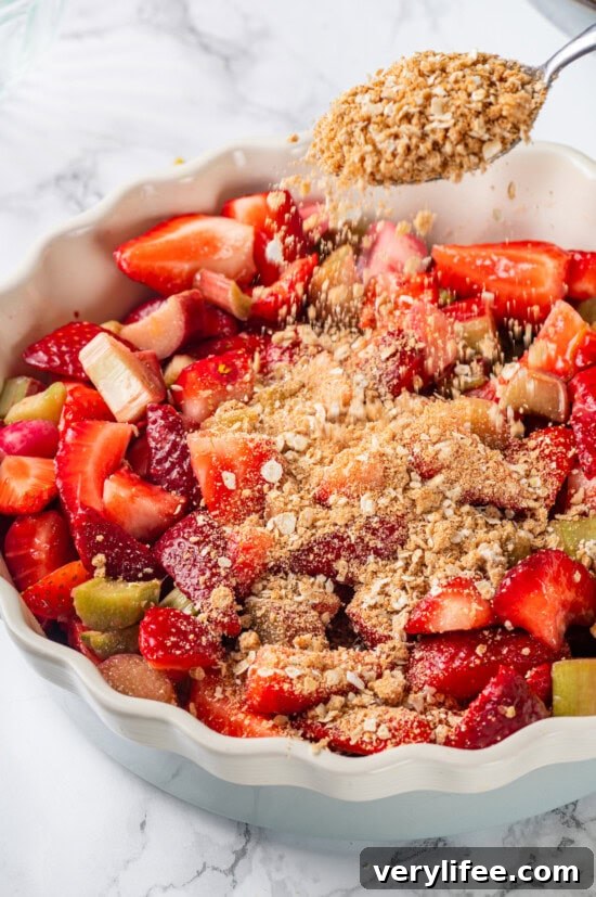 Assembling the crisp Sprinkling topping onto strawberry and rhubarb filling