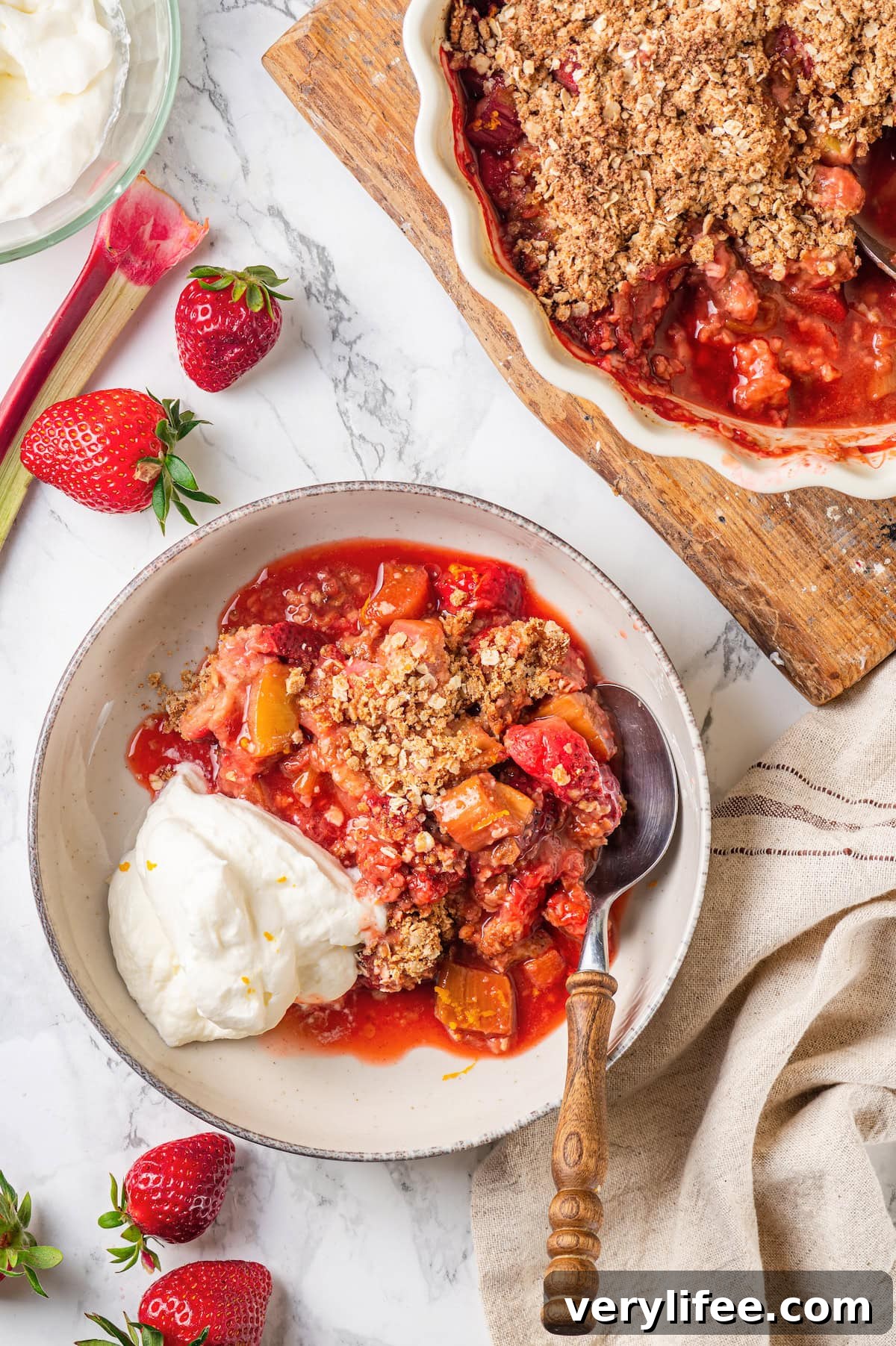 Ready to serve Overhead view of strawberry rhubarb crisp in serving bowl and baking dish
