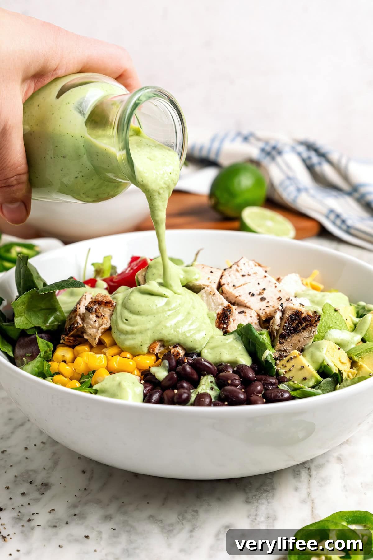 Creamy, bright, and tangy thanks to a buttermilk base, this avocado cilantro lime dressing is perfect for salads, tacos, and dipping veggies. Pouring avocado cilantro lime dressing over salad in bowl.
