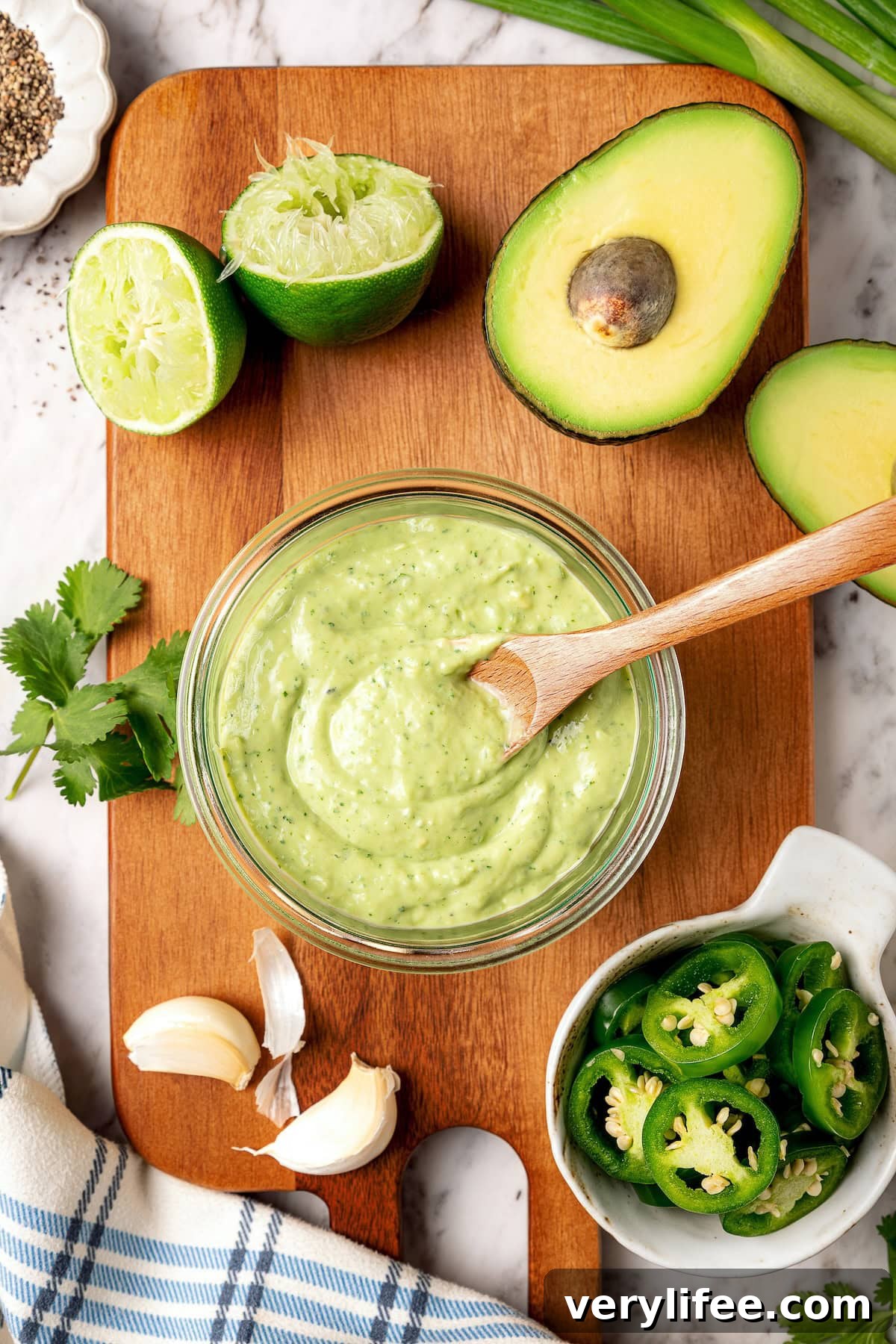 Creamy, bright, and tangy thanks to a buttermilk base, this avocado cilantro lime dressing is perfect for salads, tacos, and dipping veggies. Glass jar of avocado cilantro lime dressing with wooden spoon.