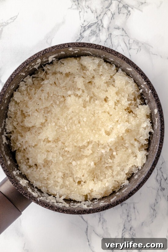Shredded coconut mixed with egg whites in a pan