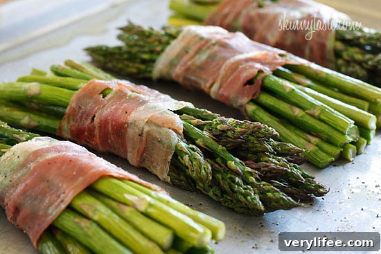 Asparagus bundles wrapped in prosciutto on a baking sheet