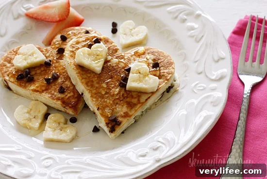 Heart-Shaped Banana Pancakes with Chocolate Chips 3 Heart-shaped pancakes cooking on a skillet