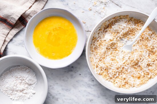 Flour, egg, and panko-coconut mixture in separate bowls.