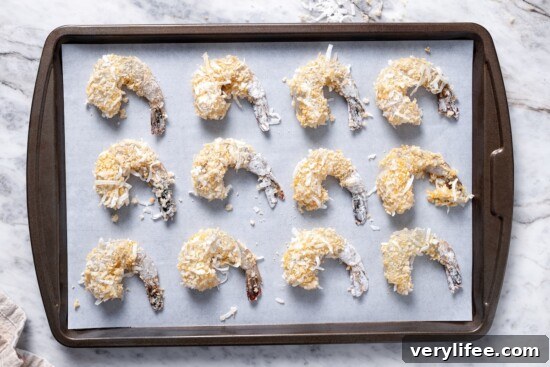 Coconut shrimp on parchment-lined pan before baking.