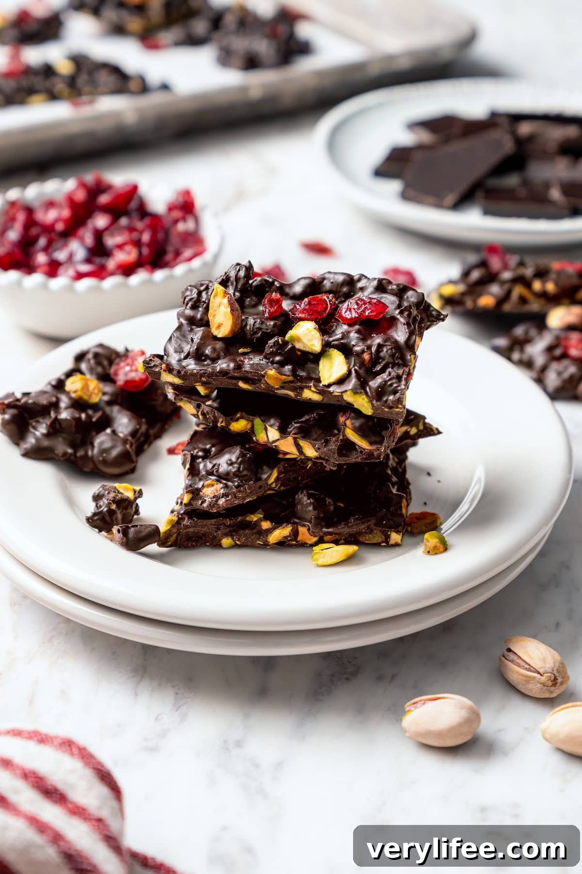 Dark Chocolate Bark with Pistachios and Cranberries Stack of dark chocolate bark with pistachios and cranberries on plate.