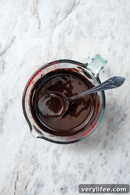 Dark Chocolate Bark with Pistachios and Cranberries Recipe 5 Melted chocolate in liquid measuring cup with spoon.
