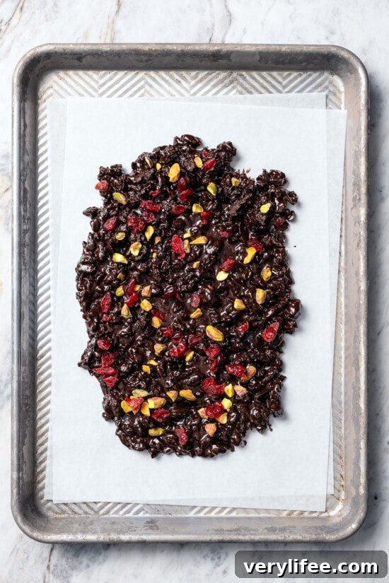 Dark Chocolate Bark with Pistachios and Cranberries Recipe 7 Dark chocolate bark with pistachios and cranberries on parchment paper.