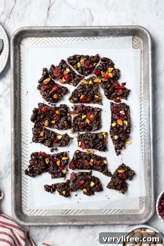 Dark Chocolate Bark with Pistachios and Cranberries Recipe 8 Dark chocolate bark broken into pieces on parchment paper.