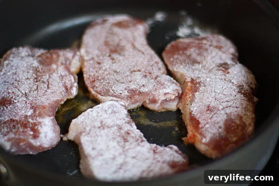 Raw seasoned pork chops placed in pan.