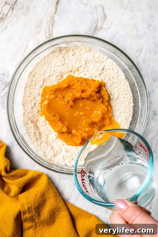 Pouring water into bowl with cake mix and pumpkin puree
