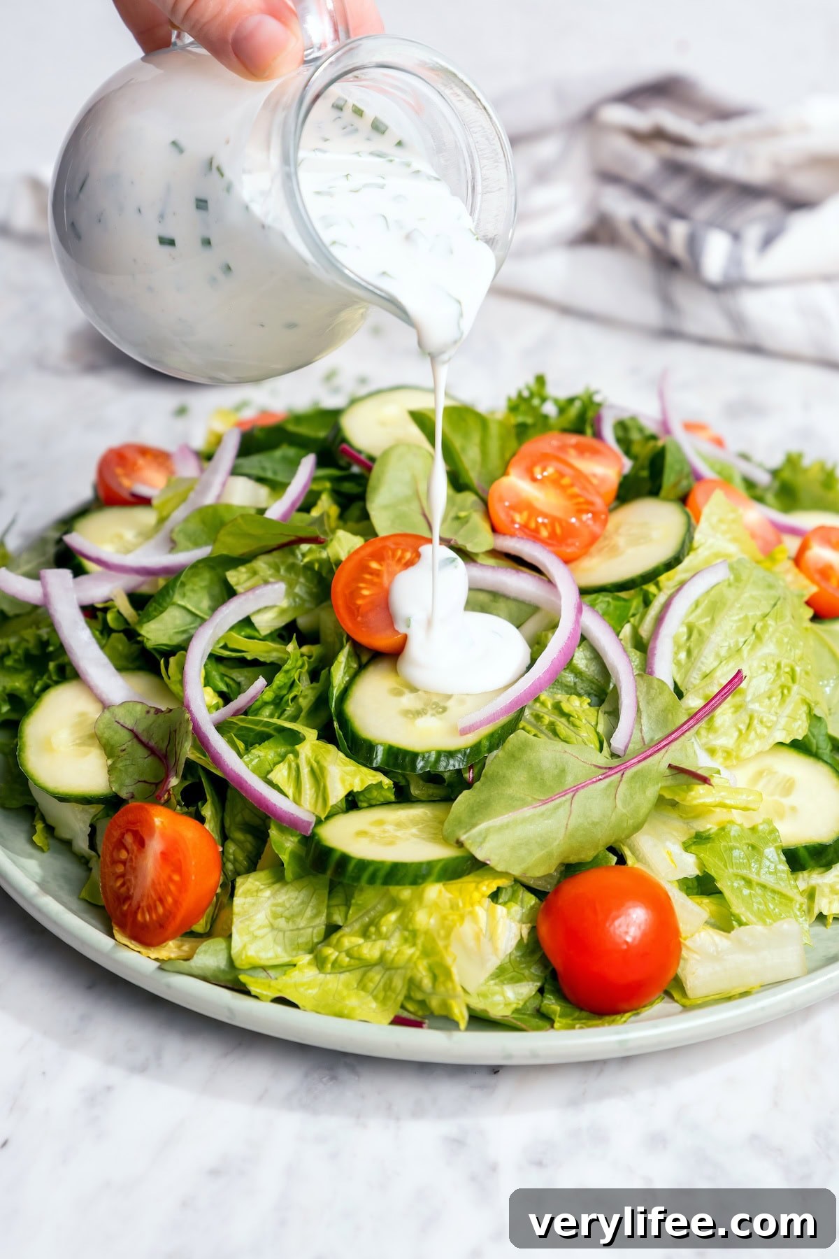 Lighter Buttermilk Ranch Dressing Recipe 7 Pouring buttermilk ranch dressing onto garden salad.