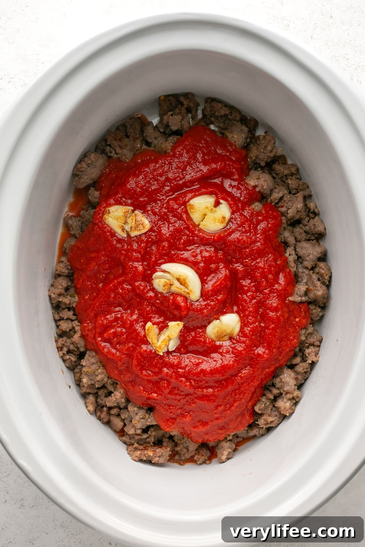 Crock Pot Sausage Pasta Sauce Recipe 6 Crushed tomatoes and garlic added to ground sausage in the crock pot.