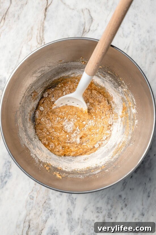 Homemade Chewy Pecan, Raisin and Chocolate Chip Granola Bars 7 Wet ingredients for granola bars in bowl with spoon.