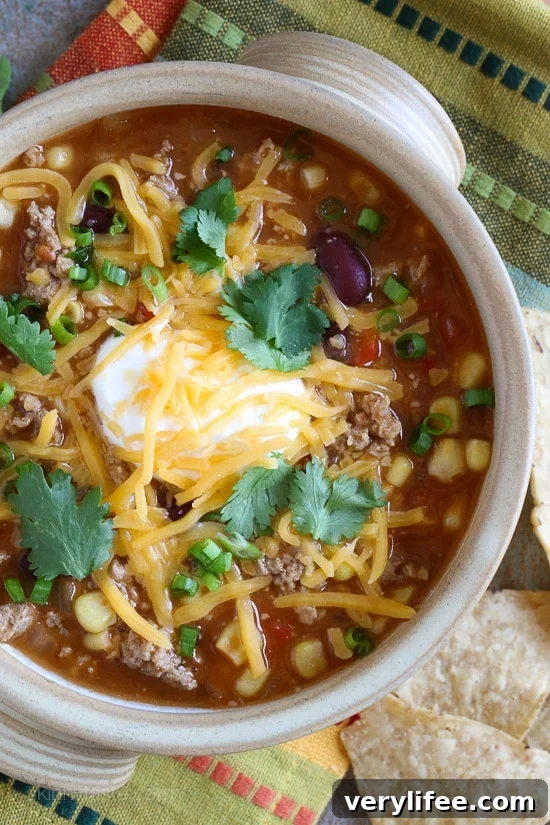 Easy Taco Soup Overhead view of a bowl of taco soup with ground turkey, topped with sour cream, cheese, and cilantro.