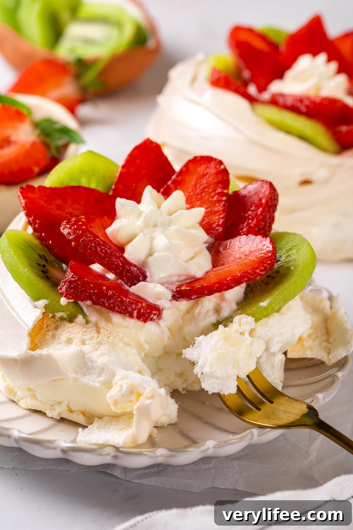 Savor a bite of pavlova Fork digging into strawberry kiwi pavlova on plate