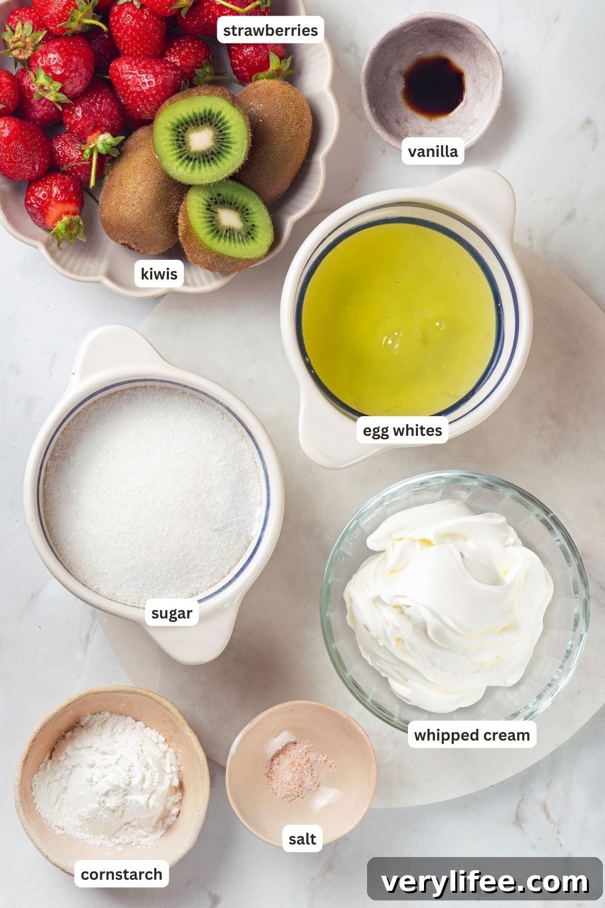 Pavlova is an elegant, light dessert that pairs airy meringue nests with whipped cream and fresh fruit. It's almost too pretty to eat! Overhead view of ingredients for pavlova