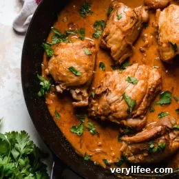 Overhead view of boneless chicken thighs in a skillet with shallots in wine sauce with red wine vinegar.